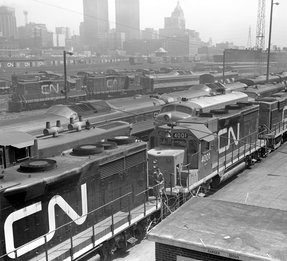 Canadian National's Spadina Yards and surrounding area in downtown Toronto was always a hubbub of activity dating back to the steam era. This 1970 view of the Spadina roundhouse and engine servicing facilities shows a great variety of power that was typical for CN back in the day, as well as some other goodies:

In the foreground are CN's only two GP35's, 4001 and 4000 (the long hood of which is visible on the lower left) coupled to an MLW RS18. Parked on the next track over is a 1900-series GMD1 (equipped with steam generator and B-B trucks) facing an Ontario Northland 1500-series FP7 and CN FPA4 (likely both together for service on the old "Northland" passenger train that pooled ONR & CN equipment). CN "Railiner" RDC cars are visible on the next track, with one in the background coupled to a pair of GP9's (4130 and 4147, the 4100-series units were equipped with steam lines for use in passenger service).  Behind them are four more 1900-series GMD1's, and some MLW S13 switchers used for switching the coachyard (one appears to be coupled to a slug - possibly a visiting hump set from MacMillan Yard?).

Visible on the main Toronto Terminal Railway tracks leading to and from Union Station in the background are CP container flatcars (6-axle trucked flats converted from old heavyweight passenger cars) loaded with early 20' containers, the TTR's John Street interlocking tower, and CN 40' boxcars lining the platforms and team tracks used by various customers to load and receive deliveries downtown (like newsprint - as evident by the yellow-doored boxcars mixed in. The Toronto Daily Star, Toronto Telegram, and Globe & Mail were known customers).

The early 70's era Toronto skyline is also visible, including the ever-present CPR Royal York Hotel, the "new" Toronto-Dominion Bank Tower built in the mid-late 60's, the CN Telecommunications building at 151 Front St. (later becoming CNCP Telecommunications, and then Unitel). And, the top of Union Station and the old CN Express building (converted into the Skywalk in the 80's) are visible just above CN's Spadina Roundhouse at the upper right (which was demolished in the mid 1980's for construction of the Skydome).