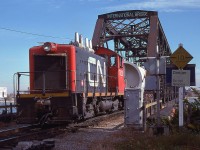 Awhhh....for the days when one could get up and personal with the International Bridge at Fort Erie. Those days are long gone. It is now the land of border patrols via fancy cameras, not a place to wander up to. This image shows something else we see no longer .......... those little reliable GMD switchers. This, along with others in the series, were renumbered to 7700s in 1985 and retired early 1990s. Note the sign regarding 'police' on the right. The local kids scribbled that, in retaliation to the fact they were chased out of the area regularly back then for using the bridge as a diving board into the river on hot days. I do not know what the cargo is that has crossed the bridge, perhaps an industrial pressure vessel of some sort?