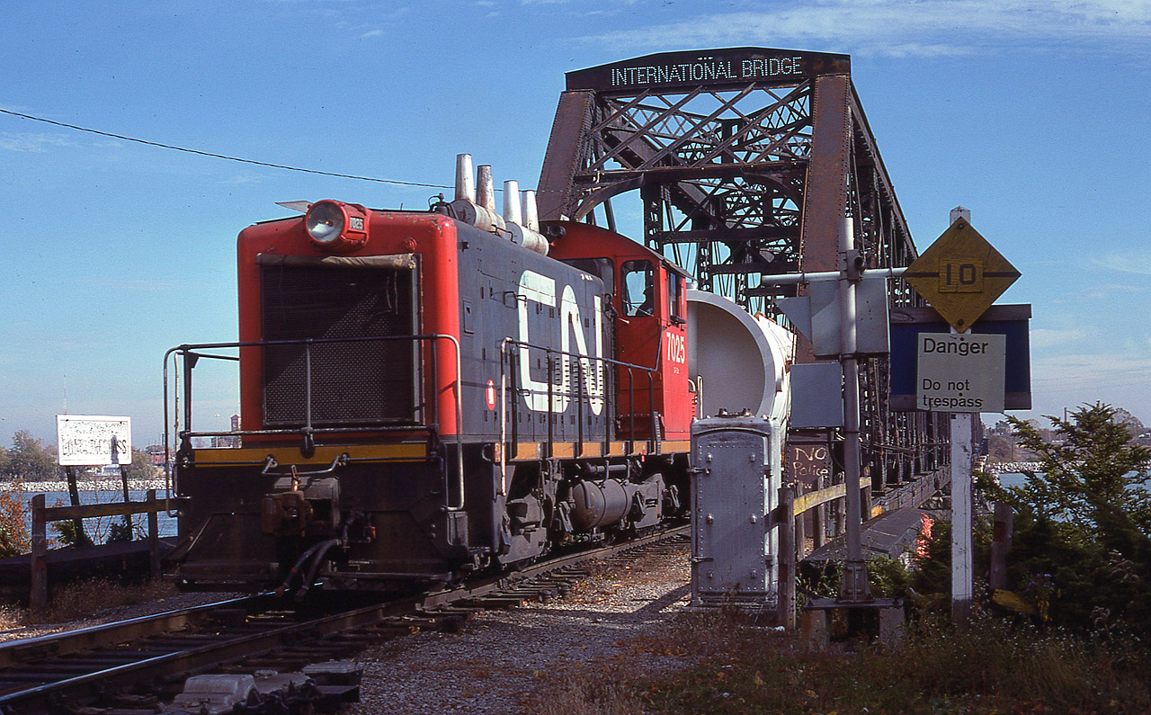 Awhhh....for the days when one could get up and personal with the International Bridge at Fort Erie. Those days are long gone. It is now the land of border patrols via fancy cameras, not a place to wander up to. This image shows something else we see no longer .......... those little reliable GMD switchers. This, along with others in the series, were renumbered to 7700s in 1985 and retired early 1990s. Note the sign regarding 'police' on the right. The local kids scribbled that, in retaliation to the fact they were chased out of the area regularly back then for using the bridge as a diving board into the river on hot days. I do not know what the cargo is that has crossed the bridge, perhaps an industrial pressure vessel of some sort?
