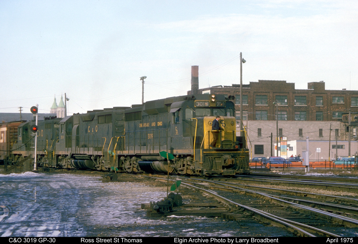 A low rumble always proceeds the appearance of another C&O freight as it struggles to haul it's Train around the sharp curve off of the ex L&PS Main onto the CASO Canada Division at Ross Street St Thomas.       April 1975