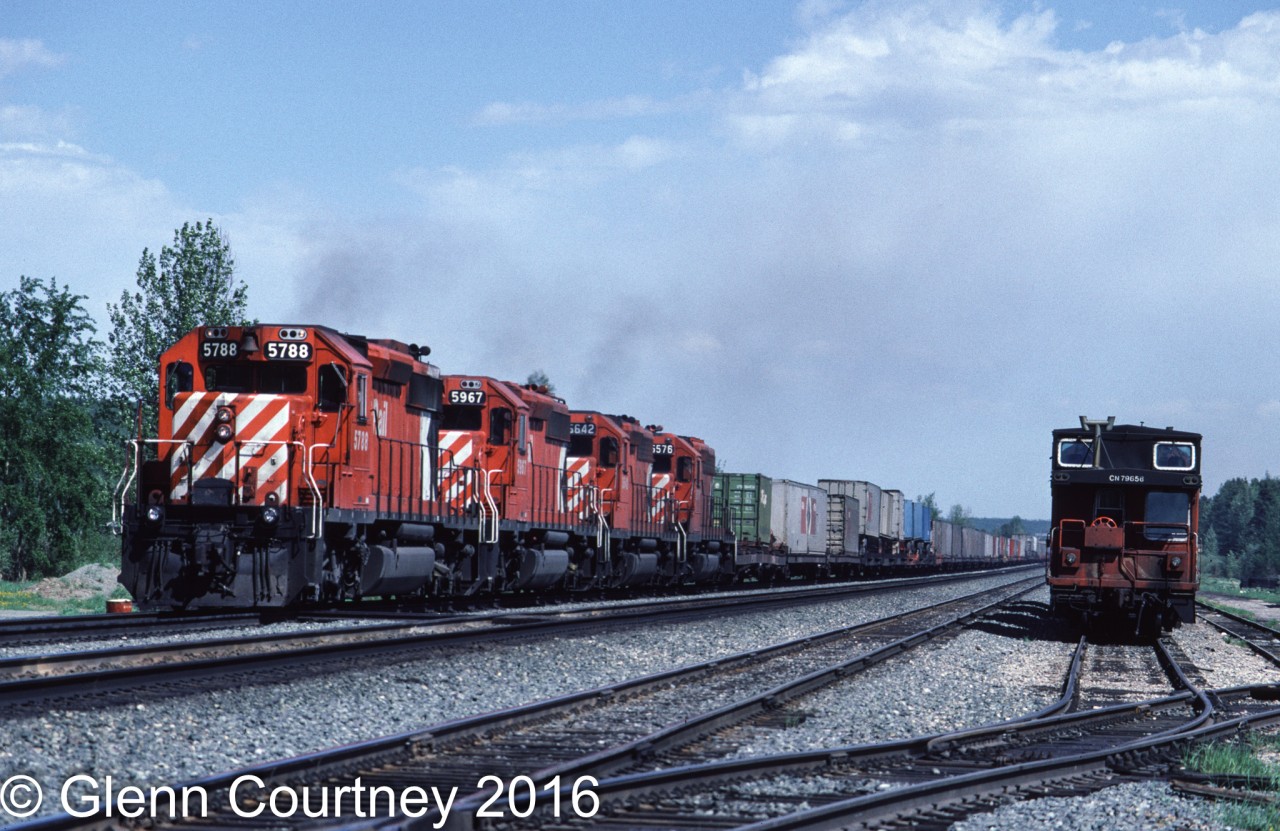 In June 1986 I was returning home from Jasper to Edmonton when I encountered a detouring westbound CPR intermodal train. I quickly turned around and gave chase. I caught up to it at Bickerdike where conveniently there was a parked CN van to give some context.