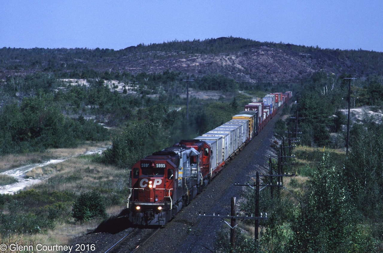 Just west of the hamlet of Wahnapitae the CPR crossed under the Trans-Canada Highway on its way between North Bay and Sudbury through a landscape still in recovery after years of exposure to mineral smelting pollution . It was usually a great place to shoot well lit shots of westbounds. Here's train #471, one of two intermodals that originated in Montreal heading for western Canada (#481 was the other). The second unit is a former Quebec Northshore & Labrador SD40-2, one of the 200+ locomotives that CPR regularly had on lease during this time period.