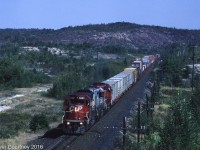 Just west of the hamlet of Wahnapitae the CPR crossed under the Trans-Canada Highway on its way between North Bay and Sudbury through a landscape still in recovery after years of exposure to mineral smelting pollution . It was usually a great place to shoot well lit shots of westbounds. Here's train #471, one of two intermodals that originated in Montreal heading for western Canada (#481 was the other). The second unit is a former Quebec Northshore & Labrador SD40-2, one of the 200+ locomotives that CPR regularly had on lease during this time period. 