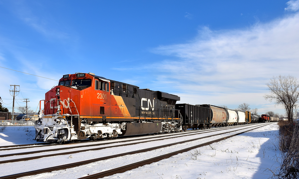 CN 369 is departing Dorval, with CN X371 at right stopped at Dorval, waiting for permission to head west. They are delayed due to an incident involving VIA 61 in Coteau which delayed all VIA Rail and CN freight trains. CN X371 would leave a half hour later.
