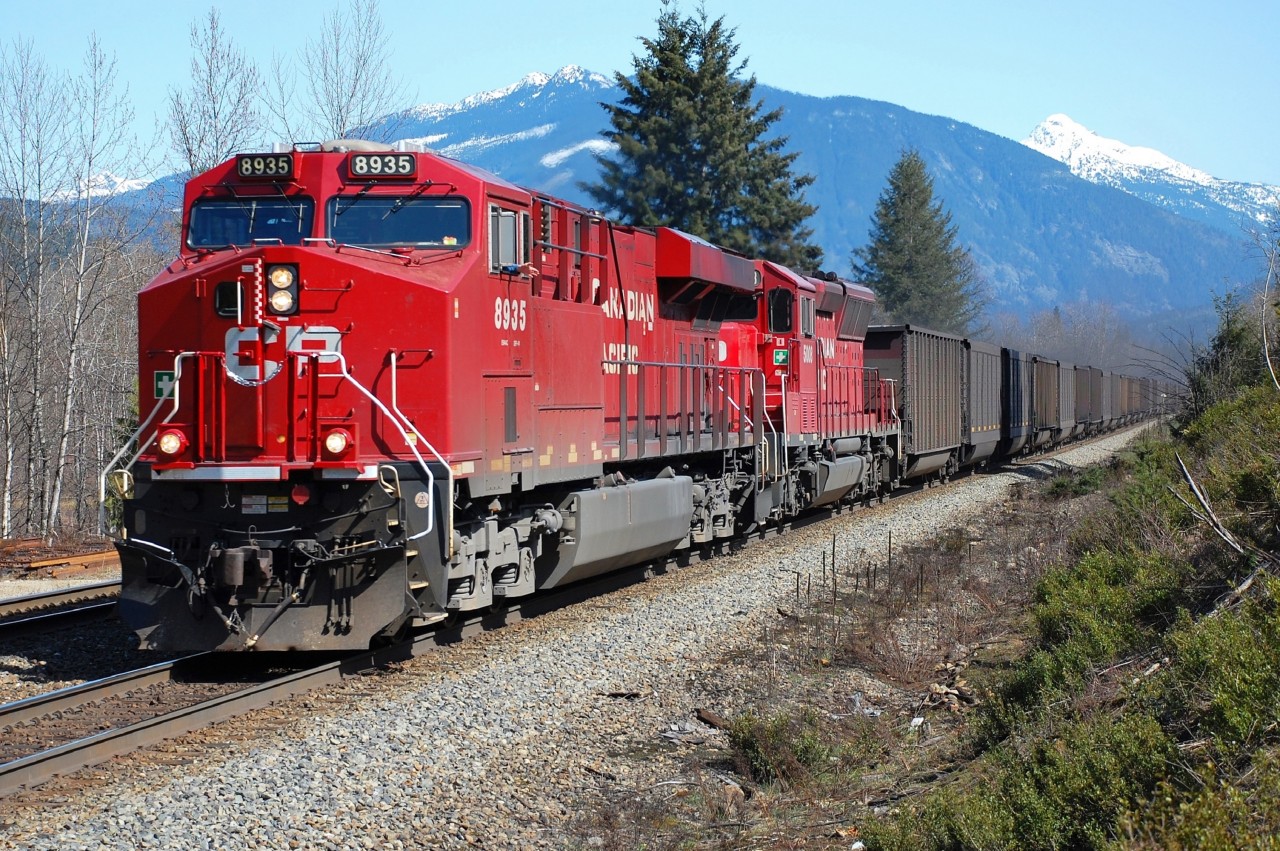 The photographer gets a friendly wave from CP 8935 as this westbound coal train hurries through Malakwa on the south track. Eagle Pass Mtn can be seen in the background and the trailing unit is SD30ECO CP 5003.