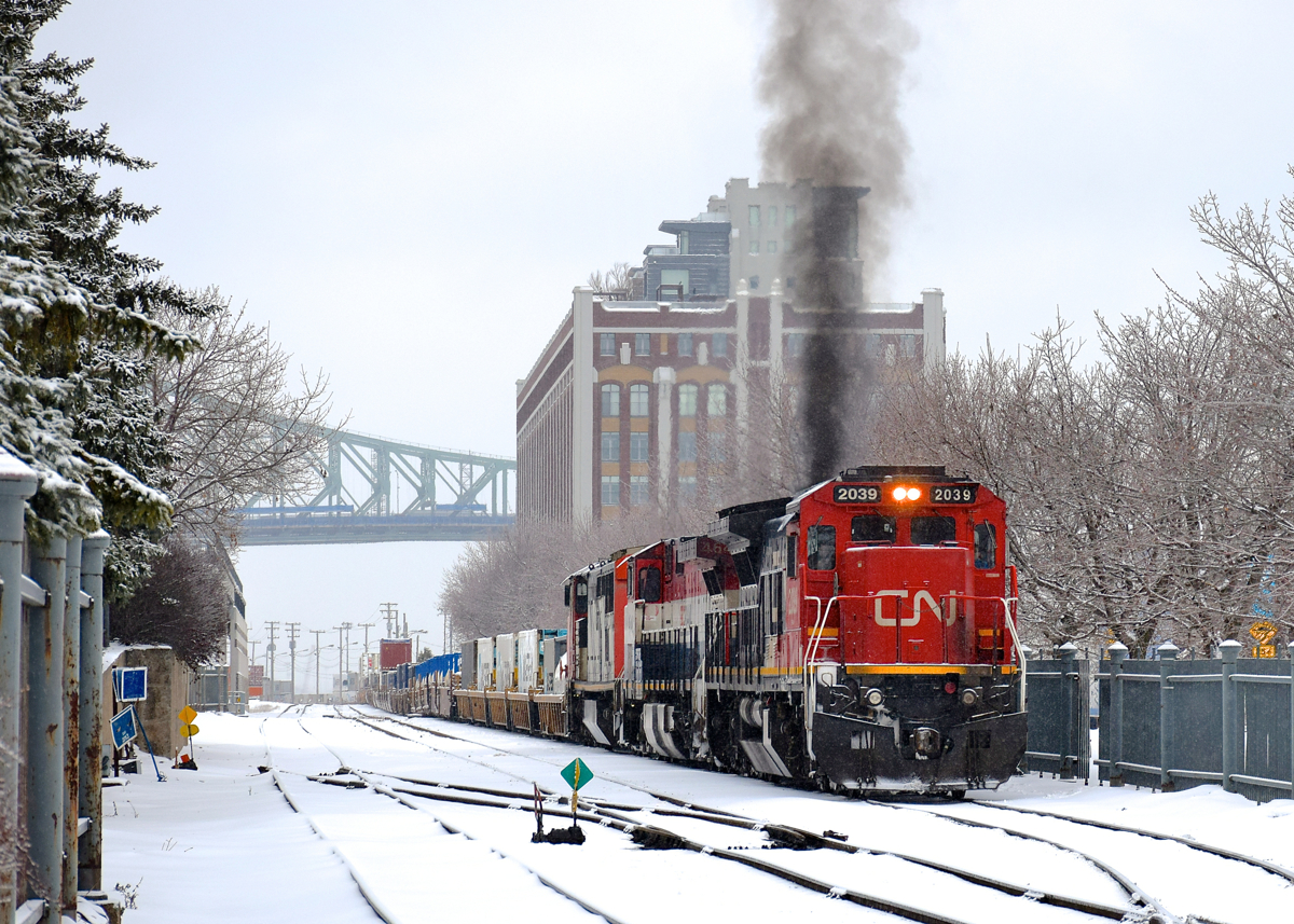 Got GE smoke? C40-8 CN 2039 belches smoke as it prepares to leave the Port of Montreal with CN 149 and 12,200 feet of platforms on the drawbar. Trailing are two more interesting GE units - BCOL 4642 & CN 2420.