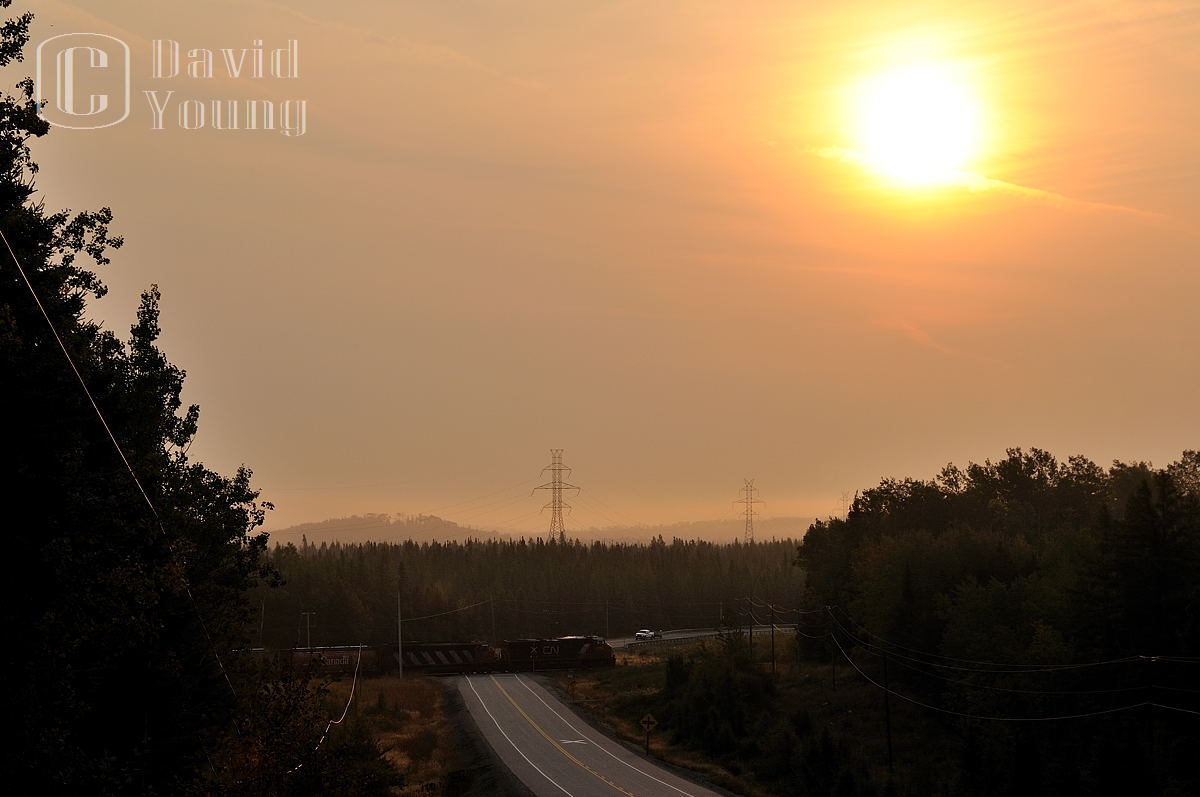 Sunrise on the Kashabowie.
Regional forest fires cover the north in a smoky haze as Thunder Bay bound grain train blasts its 14L for the Highway 11 crossing just west of the small hamlet of Shebandowan.
Of note: This was the first DPU'd train CN ran on the Kashabowie. I can't recall the number of cars but I believe it was in the neighbourhood of 150-160 cars. An absolute monster! And this practice today has become common on bulk trains into the Lakehead, some pushing this threshold in the 200+ car total. Power CN ES44DC 2236- CN SD50F 5459 with CN ES44DC 2267 pushing on the rear