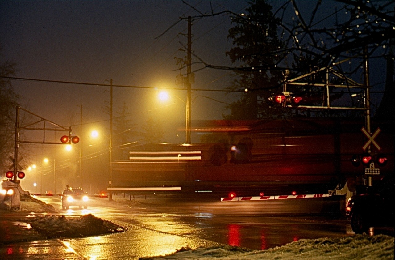 Light rain and fog fills the air in Milton as a CP westbound led by a SD40 "Red Barn" storms past the old cross bucks protecting Martin Street crossing in Milton. The old signals have seen the passage of countless trains over the decades but will soon be replaced by newer technology, including LED lighting. I've always liked night photography in the rain as it adds a nice glow to the landscape, and you can never go wrong with a bit of fog thrown in for good luck :)