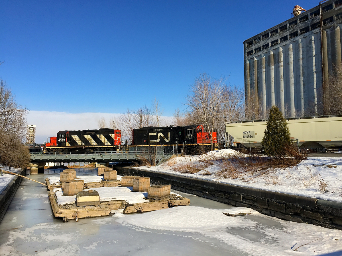 GP9's CN 4102 & CN 7054 back a cut of grain cars past grain elevator #5 in the Port of Montreal.