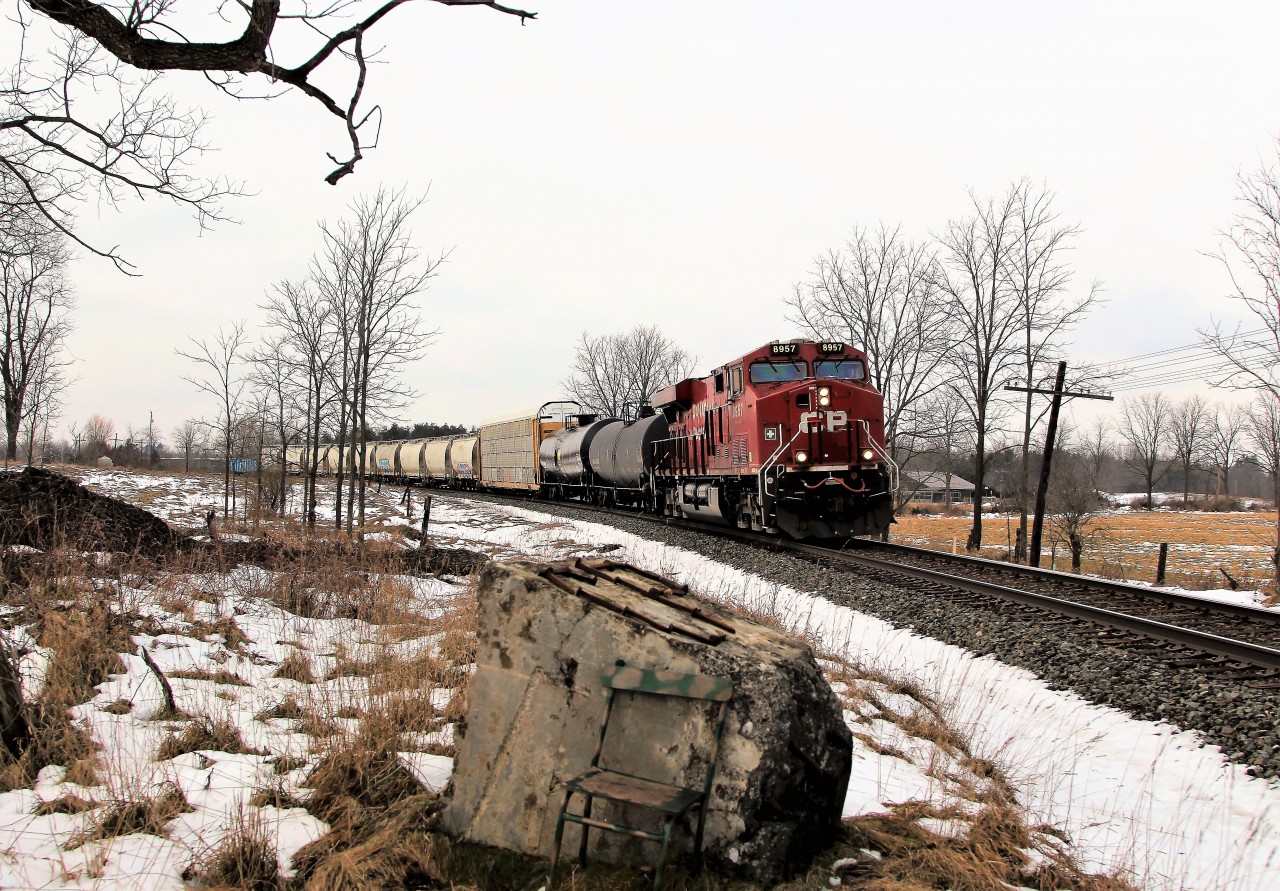 This picture is more about the rock and chair than it is about the train itself. This spot was one of the local hangouts in days past of Mr. Bill Clarke, sadly now deceased, and Mt. Arnold Mooney. It is know as the Clarke rock and Mooney chair. The rail spikes on the rock have had various designs over the years but were scattered in a storm and then rearranged by kids. They now bear the CP logo done by another resident of this area. That would be me.