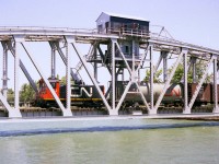 In somewhat of a response to Glenn Cherry's recent submission showing TRRY 1859 rolling along trackage that was newly laid in 1997 and the canal bridges in the background, I decided to dig up a shot of a train on that former lift-style Bridge 20. Unfortunately back then it was dicey at best to try and drive over bridge 21 to give chase, but rather follow the train on foot. And that was no piece of cake either. I did manage one shot on each side of the bridge plus this image taken as it is crossing westbound. But back then, with no zoom lens available, this was as good as it got. Pictured is CN 7166, returning to Port Colborne from Nickel, as indicated in an old CN timetable. The switcher is an SW8, built 1951 and whole series gone by 1989. I must have looked like some sort of deranged nut running around out there on a HOT day, but, well, we all have our weird habits.:o)