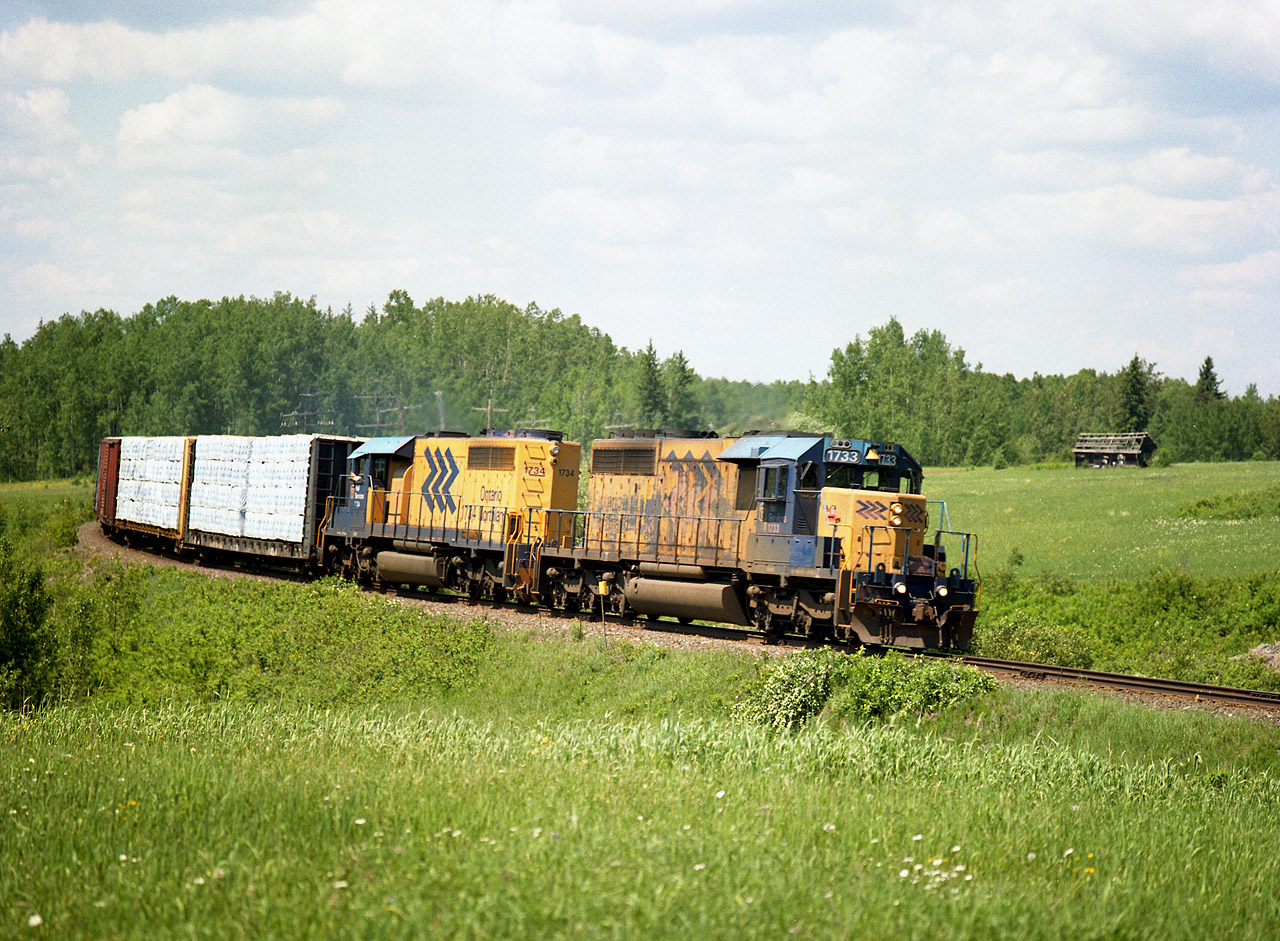 ONR 1733 and 1734 head southward on a beautiful June afternoon. That old shack in the field probably is all there is left of South Mindoka. The sawmill town died in the 1940s and was abandoned by 1960. Another ghost town of the North.  Only a mile up the line from here was the community of Mindoka itself, still a namesign on the ONR. It once had bunks for the T&NO employees as well as the Temiskaming & North Ontario railroad station. It too, vanished.