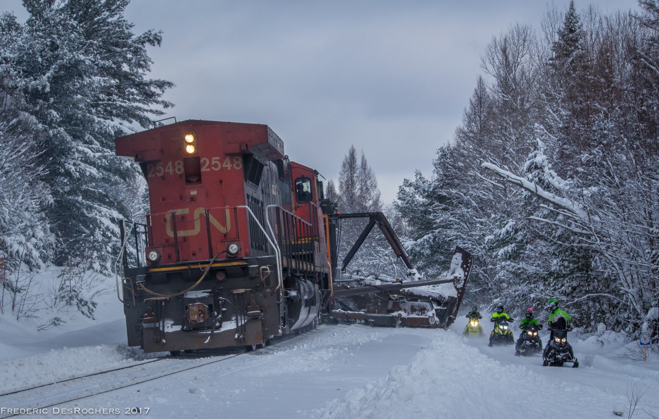 The CN spreader heads North through Utterson, next to some rather confused snowmobilers.