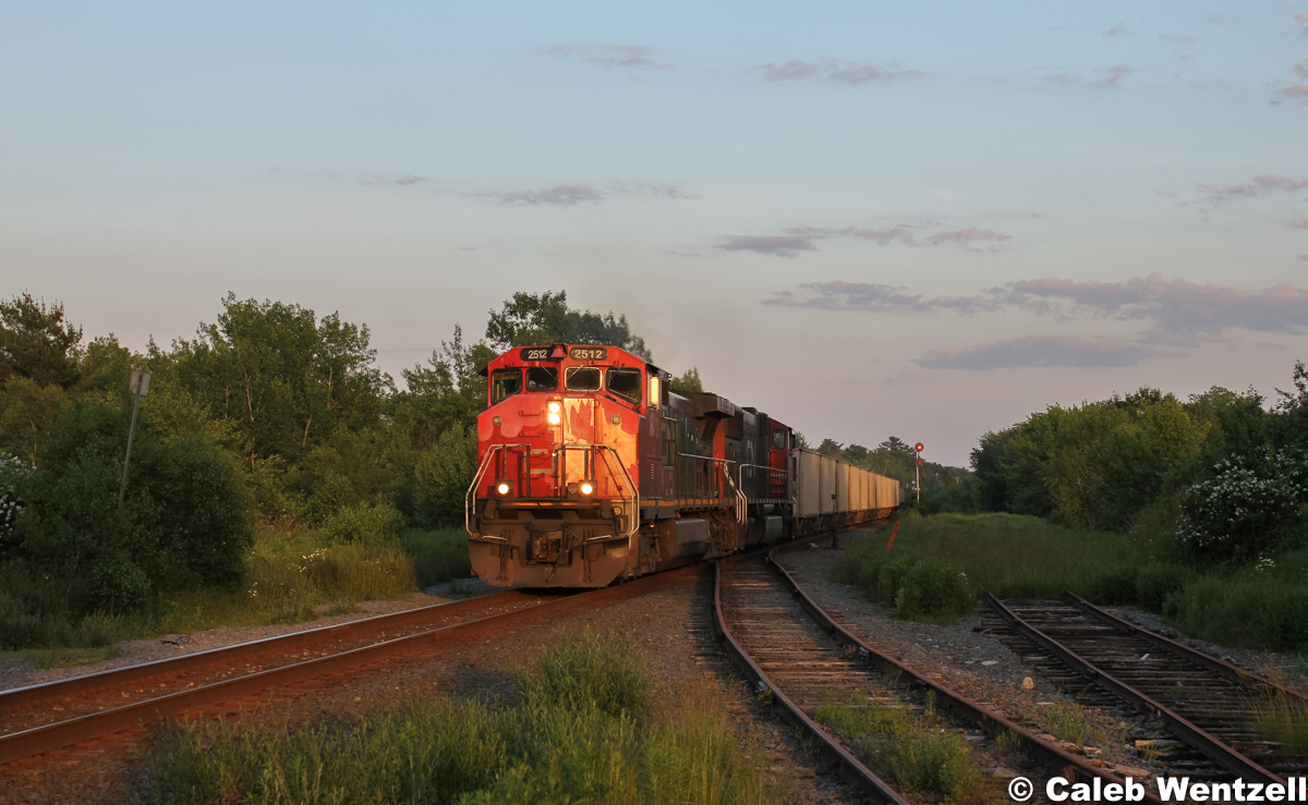 CN 2512 leads a train of empty gypsum cars from Wrights Cove en route to Milford, NS.  The train is catching some golden rays of run with a beat up locomotive on the point.
