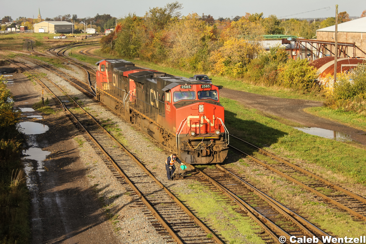 CN 2585 and 2558, (both C44-9W's) idle ahead of the switch, while the conductor is currently changing the points so the power can reverse onto the GP40-2W awaiting pickup to assist with the train's tonnage for the remainder of the trip to Moncton, NB.