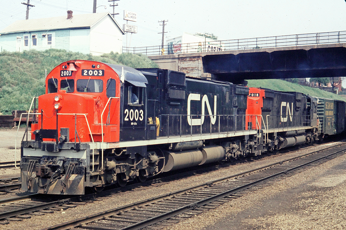 MLW C-630M 2003 with 2018 pass under the Bay St. bridge into Hamilton Stuart St. yard.  This is train 466, one of many trains each on the Grimsby Sub.  
Acorn lumber can be seen at the top left of the picture.  This is now Hutch's Restaurant.  The Bay St. bridge has been replaced with a new span. Where I am standing to take the picture would be about where the north track is for the new West Harbour GO station.  This is now in the area of the STUART interlocking.