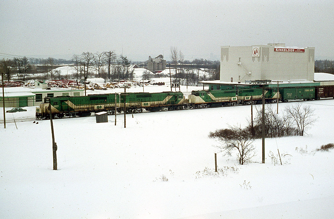 I was very fortunate this eastbound was held at the signal just below the Waterdown Rd bridge in Aldershot. It gave me a chance to grab several shots of it before the light faded. A difference of ten minutes late day makes all the difference in the world. A four unit freight of all GO power was a rarity indeed; this was my only sighting.  The power short CN was leasing whenever they could. GO 9801, 9804, 710 and 709 power this train. GO was renumbering all of their 9800s to 700 series at the time. The Kirkelder Spray Mister building is much better known as Aldershot Cold Storage by us photographers of the day. It has been now been leveled. And the main is now three tracks plus two Aldershot yard leads are in the foreground. In the far background is a structure of Cooke Concrete, another defunct business of the area. Only that low building by the lead engine, known to me as "FX" which was a theatre outfit of some sort, is still there to mark the territory.