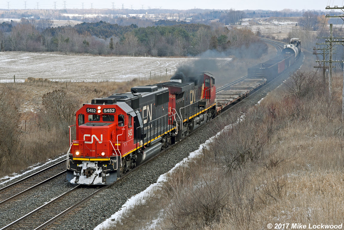 Not typical of CN freights, 5452 and 2560 lead 517's 15 car train through the sag at Newtonville. 1357hrs.
