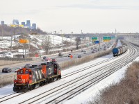 <b>Running around.</b> GP9's CN 4102 & CN 7054 have just  shoved 7 grain cars onto a cut of grain cars on the freight track of CN's Montreal Sub and are heading west light so that they can run around their train and head east to Southwark yard. The grain 7 grain cars had been set off by CN 874 on track 29 in Turcot Yard the day before. In the background at left is the skyline of downtown Montreal.