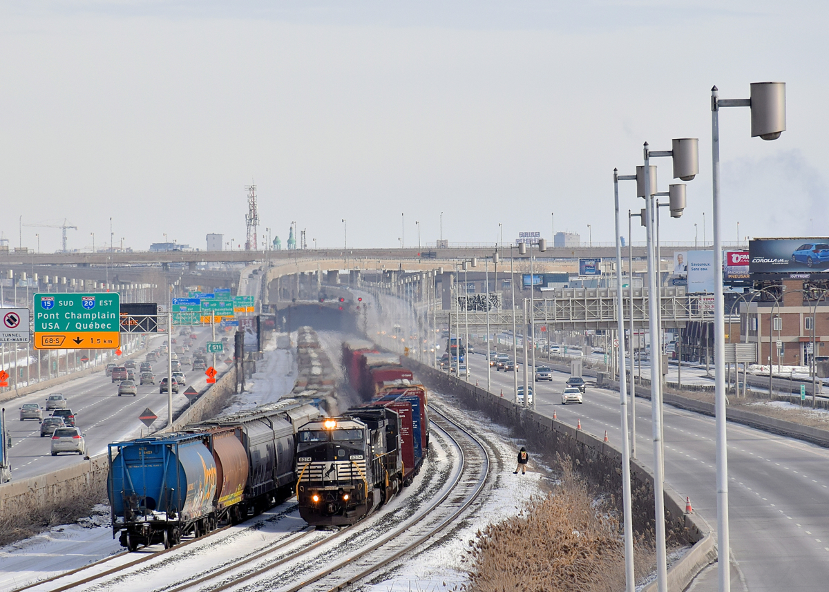 A pair of ex-Conrail Dash8's (NS 8374 & NS 8392) lead a customarily short CN 529 past a long cut of grain cars as a CN employee gives a rollby at right.