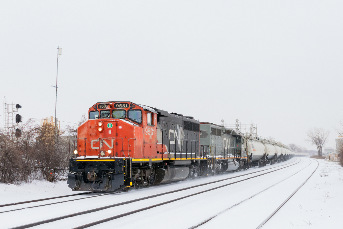 CN 585 with two strings of TankTrain loads (34 cars total) for Maitland, Ontario is westbound through Dorval on a snowy morning. Leading is GP40-2L(W) CN 9531, with SD40-3 GTW 5951 trailing.