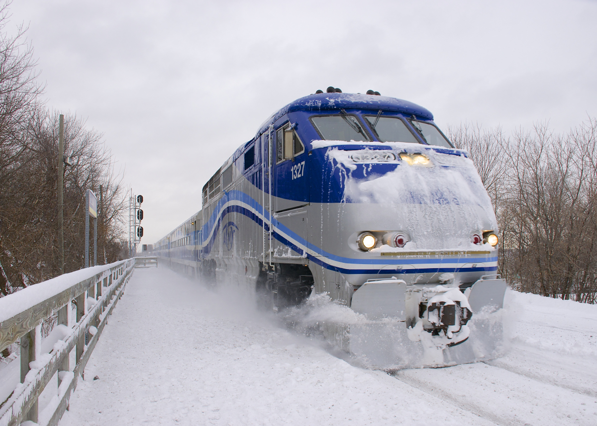 After a heavy snowstorm, snow covered AMT 80 arrives at Lasalle Station with F59PHI AMT 1327 leading.