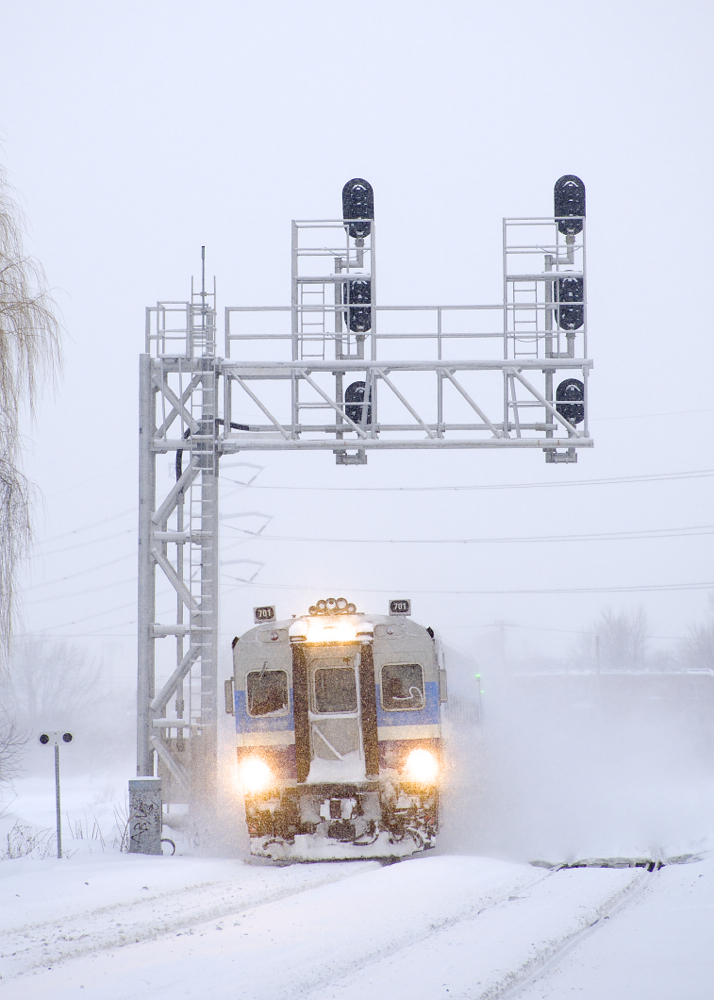 With a lot of rain and warm temperatures recently, Montreal has lost just about all the snow it had, but a couple of weeks ago there was more than enough to go around as an AMT deadhead move with cab car AMT 701 leading passes under a signal gantry near Lasalle Station. The train is on its way to the South Shore to bring more commuters to downtown Montreal.