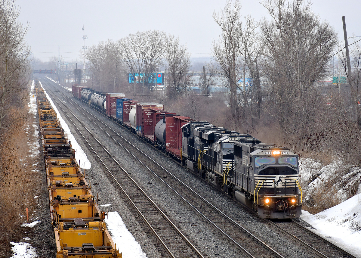 An ex-Conrail SD60I leads a pair of ES44AC's on CN 529 as it approaches Taschereau Yard. At left are stored well cars.