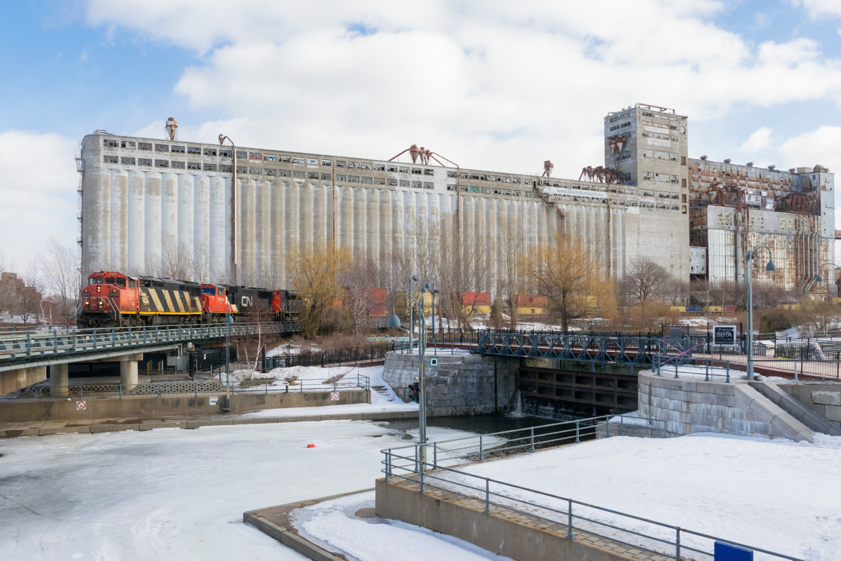 Operating as CN 596, a very late CN 148 is coming into the port of Montreal with CN 2425, CN 5664 & CN 8850 leading 14,000 feet of containers into the Port of Montreal as it passes grain elevator #5. Normally this train would arrive here in the middle of the night, but a large rainstorm last night caused high water levels in the port, necessitating that the train be tied down at Turcot West all morning.