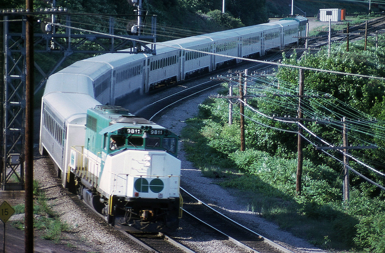 Back in the days before the bilevel cars on GO Transit, we see the evening Hamilton-bound train taking the curve at Hamilton Jct and heading toward the old CN station. Moving along just a hair too quick for my camera setting but still a presentable photo. In 1975 all GO locomotives were relieved of their 9800 series numbers, so shortly after this photo was taken, the 9811 became 703. Unfortunately I did not record the trailing unit.