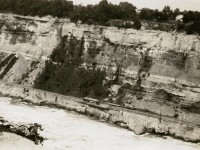 Tourists on the Great Gorge Route get a good close look at the Niagara river. A lot of rock has come down since this photo was taken by my Grandfather in 1928. The line opened in 1895 as the Niagara Falls and Lewiston Railroad, running from Lewiston to the Honeymooner Bridge near the present day Rainbow Bridge. The line was merged and connected in 1902 with the Niagara Falls Park & River Railway line on the Canadian side and became known as the Great Gorge route. Rockfalls and landslides were a constant problem. The line on the Canadian side closed in 1932. A portion of the line is visible north of the botanical gardens and butterfly conservatory. The line on the American side closed in 1935 after a 5000 ton rock slide came down just north of the whirlpool bridge. On the American side a trail runs on the roadbed from the Rainbow Bridge to below the whirlpool bridge. Location approximate, editing by the moderating team.