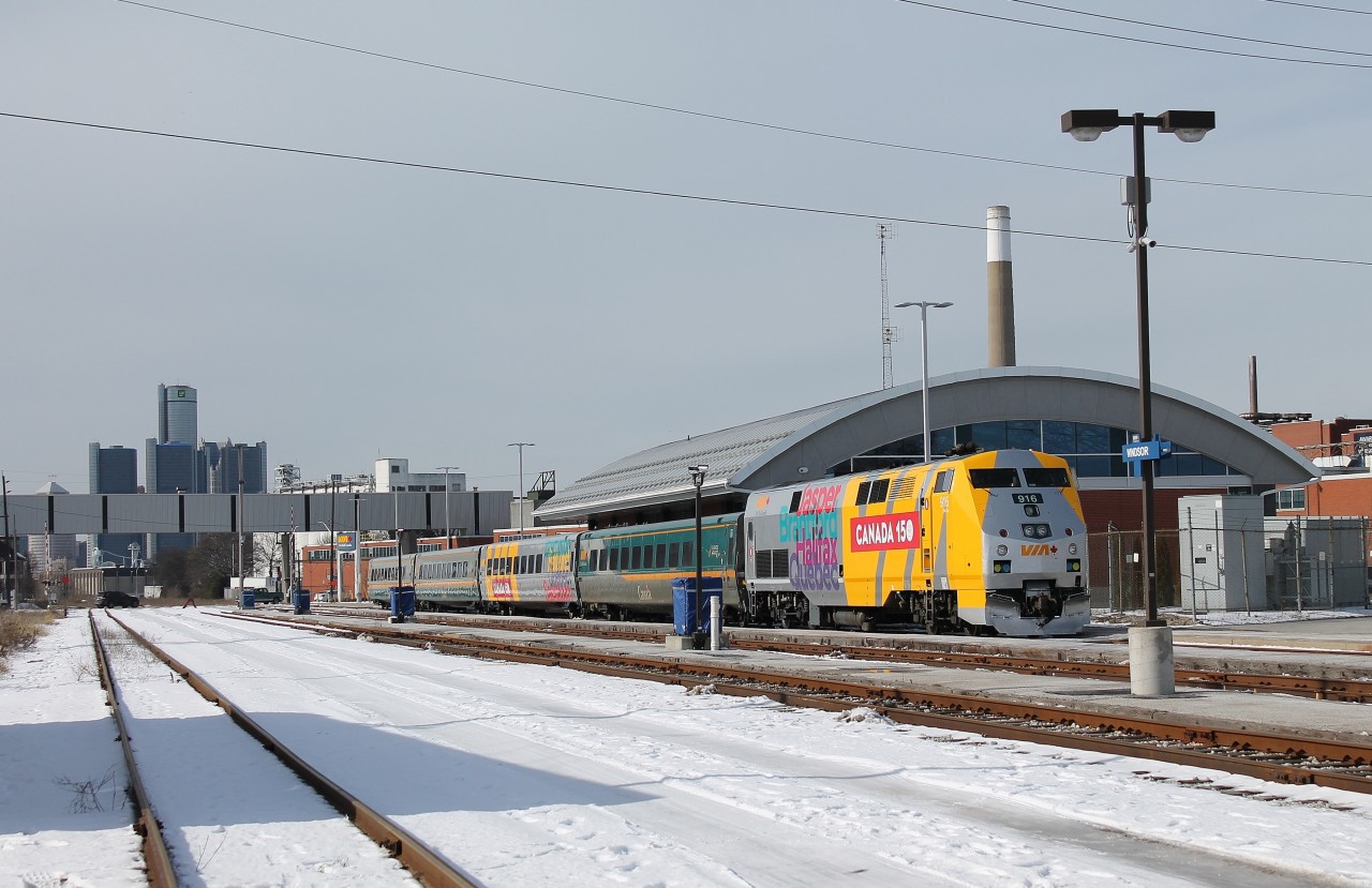 VIA 76 bound for Toronto waiting to depart Windsor with a newly wrapped VIA P42DC commemorating Canada's 150th anniversary. You can see Detroit's skyline in the background, most notably the GM Renaissance Center which is home to GM's world headquarters and a Marriott Hotel.