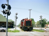 It is a rather hot July 1st, and CN 7166 is about to cross over the canal via Bridge 20, to fetch a few loads.
The Sidekick has just grabbed a shot of the unit passing CN Port Colborne station so we've got this move covered. (she earned her keep) Bridge 20 was removed 20 years later, and the track was realigned curving north thru the pavement on the right, running now up the west side of the canal.