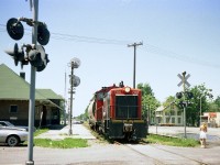 It is a rather hot July 1st, and CN 7166 is about to cross over the canal via Bridge 20, to fetch a few loads.
The Sidekick has just grabbed a shot of the unit passing CN Port Colborne station so we've got this move covered. (she earned her keep)  Bridge 20 was removed 20 years later, and the track was realigned curving north thru the pavement on the right, running now up the west side of the canal.