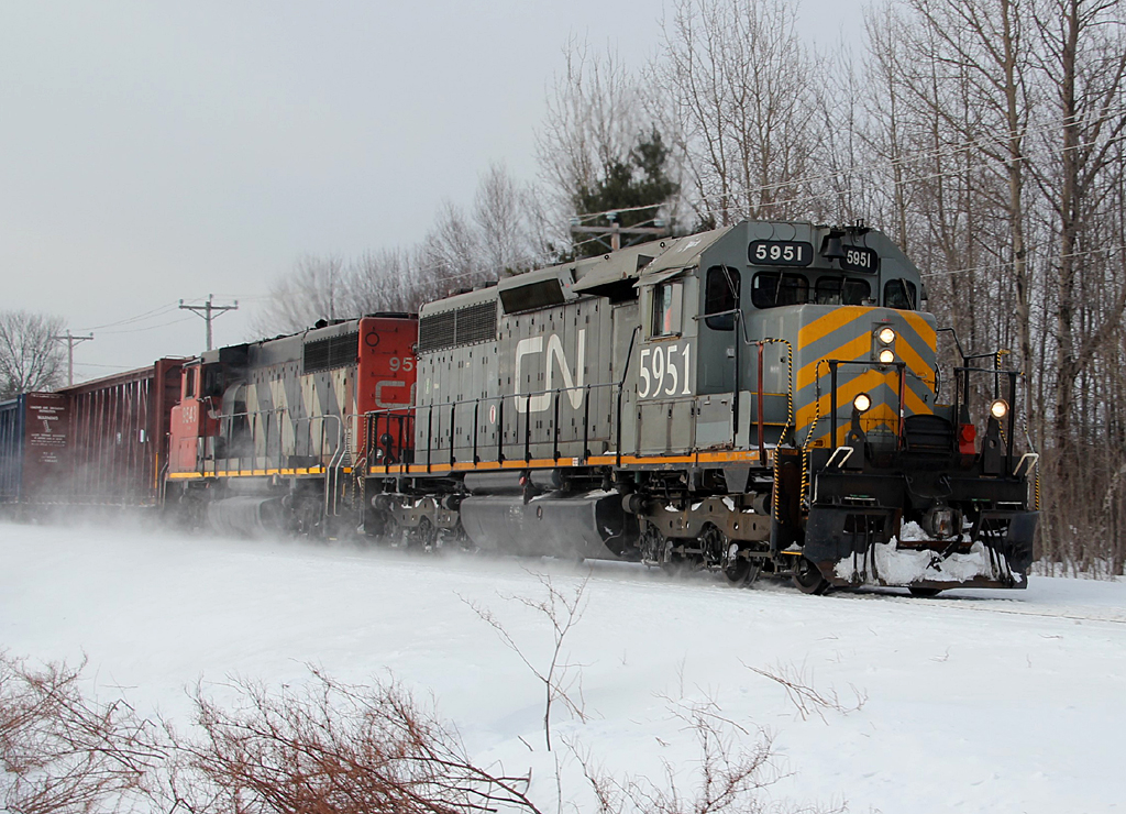 On a very cold winter day, GTW SD40-3 5951 kicks up the snow, at St-Paulin, along with GP40-2L(W) 9543, pulling 69 cars