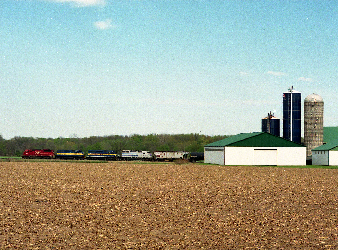 I heard on the scanner of this eastbound while sitting in my quiet spot down by Trout Lake park. A place I could snooze if boredom warranted. Problem is, it was afternoon and the sun was a real stinker for eastbounds. So I motored over to Marshall Farms, just west of Innerkip and waited it out on the laneway. The photo I suppose is a bit far off, but still, its a nice power combination...... SOO 6046, DME 6070, 6088 and CITX 3005. Beats most anything I see these days. :o) And for me, this is very recent.