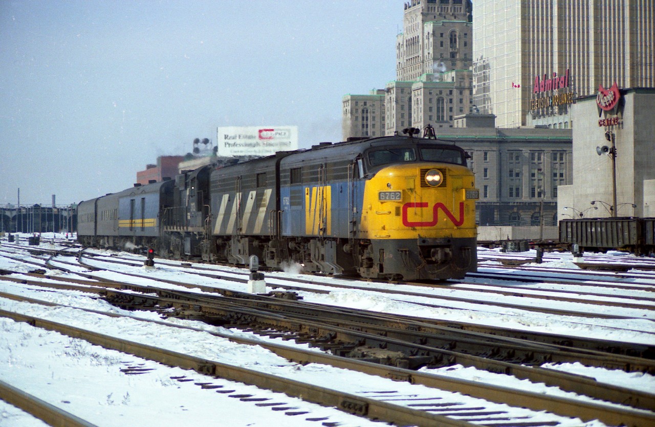 It was thirty-nine years ago this morning as I post this; Feb 26/78, also a Sunday; and at 10:50 on a not-all-that-bad morning, roughly 40F (3C?) the Rapido #62 is seen pulling out of the sheds at Union Station making its start to Montreal. It is transition time in the early years of VIA, thus we have a "CN" on the nose and a "VIA" on the sides of the lead 6762. Behind, still in traditional CN, are B unit 6862 and RS-18 #3113. The 11 cars in tow are of various paints, as the move to standardize the VIA yellow and gold was just under way. Note the old O'Keefe Centre on the right. No chance of shooting from this angle any more........