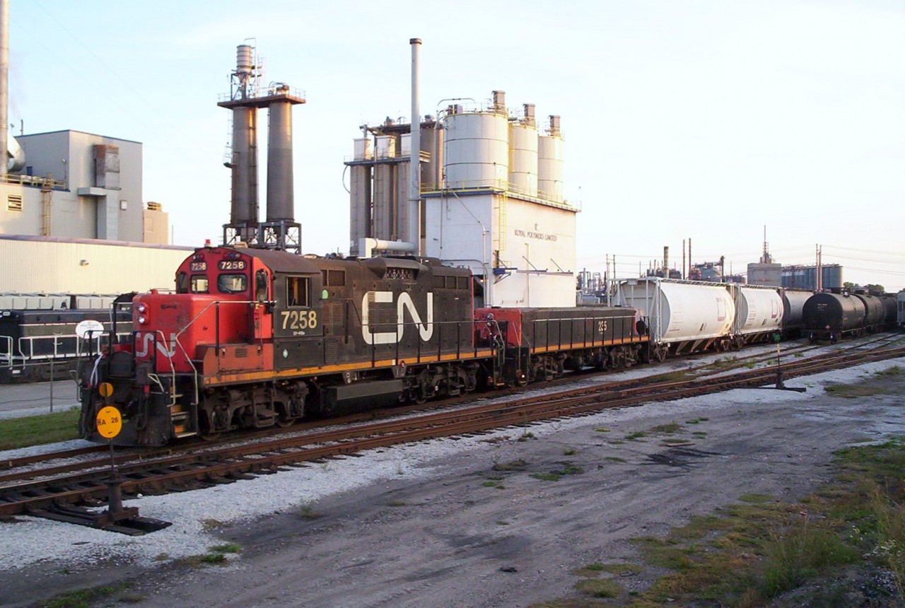CN 7258 switches cars in the small yard on the "farm track" in Sarnia, Ontario. This yard was used to store cars for Royal Polymers and Cabot Carbon. The Royal Polymers SW800 switcher 8620 can also be seen in the background. Royal Polymers closed with the plant demolished and the little switcher sold elsewhere.