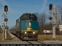 VIA 6441 starts to accelerate out of town as it splits the signals at "VIA Lacasse", MP 99.1 VIA Chatham Subdivision, in Tecumseh, Ontario.  In the distance the GM World Headquarters building in Detroit, Michigan can be seen looming in the skyline.