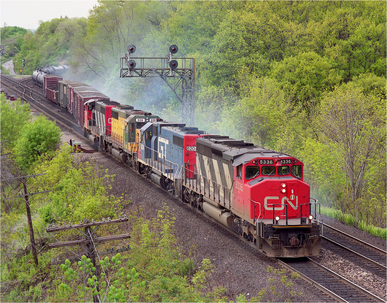 In this view from the railfan's walkbridge (as we call it)CN's #382 is smoking up pretty good, this due to overheating sticky overheating brakes, I assume, as it is a long downhill grade from Copetown to Bayview. A 'smokey train' was once common here, before roller bearings became common in the 1970s, and hotbox detectors came into existence. Power on this train: CN 5336, GT 6204, NRE(National Railway Equipment) 886 and CN 9410.