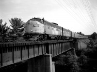 The VIA up from Toronto is running a little bit late this day. Time is around 1800 rather than the 1715 it normally pulls in at CN Boyne. Every minute helps. Gives more light to the nose of the leader:o)as the late day sun swings around. In this B/W view VIA 6507 and 6622 are seen crossing the bridge over the valley where the former line out to Parry Island and Depot Harbour used to run. Now, like in most other pulled up lines, is has been converted to a walking trail.(the line was pulled up fall of 1987)
This image is from a scanned 4x5 negative, 400 ISO shot at 200f8 with the Speed Graphic.