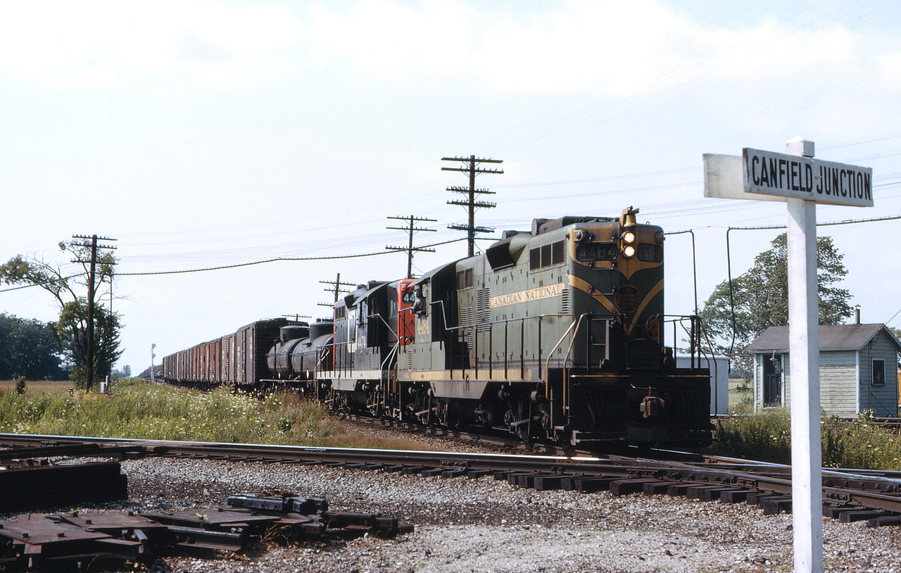 With the engineer looking intently at the rear of this train, a CN eastbound arrives at Canfield Junction with GP9 4484 in green and yellow, and 4474 in the "new" CN scheme.