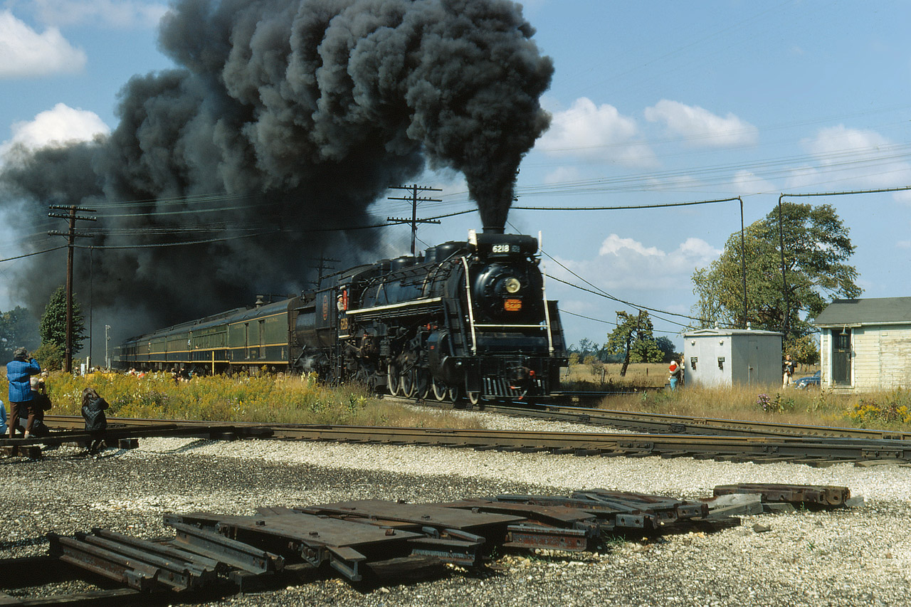 The Upper Canada Railway Society sponsored an excursion from Toronto to Ft Erie on Oct 1, 1967. The destination is simple but how they got there is far from that. Leaving Toronto Union Station at first good light, the train operated via CN's Oakville Subdivision to Hamilton. From there, it operated via the CN Hagersville Subdivision utilizing the street running along Ferguson Ave, crossing the TH&B mainline and climbing the grade of the Niagara escarpment to Rymal and beyond to Caledonia. Turning east on the CN Dunnville Sub, it continued via Dunnville, Port Colborne and Ridgeway, until arriving at Ft Erie. The return trip was via the Cayuga Sub to Welland Jct, the Humberstone and Welland Subdivision's to Clifton ( outside Niagara Falls) and then the Grimsby Sub to Hamilton, and finally back to Union on the Oakville Sub again. 
Here we see Doug's image of a runpast taking place over the diamonds at Canfield  as shutters click and movie tapes roll.