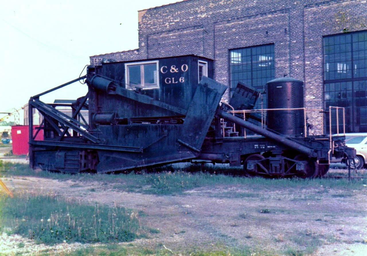 On this dreary May 1975 afternoon, C&O GL6 sits patiently outside the roundhouse in St. Thomas, ON hoping for something to do before someone decides it no longer has any use. This Jordan spreader was built around 1924 and is a standard 2-180, translating to center cab, low front blade, articulated side wings and pneumatic cylinders. It is an early front braced riveted design, and may have been rebuilt from a knuckle type unit.