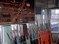 A rare look inside the West Toronto diamond interlocking tower in February 1964, not too long before it was demolished. A Saxby and Farmer interlocking machine dating from the 1900's was manually controlled by the tower's "leverman" to direct the movements of trains through "The Junction" area. The various coloured levers control track switches (blue), switch locks (black) and signals (red) through mechanical linkages of connecting rods and bell cranks that run out of the tower, along the railway lines, and to the switches and signals they control.  A large track panel display shows the various lines and routings, along with indicator lights (note the illuminated lights on the board corresponding with the CN train passing by outside). The tables of numbers on the display show the sequence of levers that must be pulled by the leverman to line specific routings.
<br><br>
Physically, the interlocking tower was located at the southeast corner of the West Toronto diamonds where CN's Brampton Sub (later Weston Sub) crossed CP's North Toronto Sub, and movements across both lines were directed by the tower. CP's Galt Sub (that passed by just to the west) had a connector track to the MacTier that ran northeast and bisected the diamonds. The former TG&B line (that had become an industrial spur) came off the CP MacTier Sub and ran south by the tower with its own set of diamonds, as shown on the track panel display. And, the tower also controlled movements to/from the MacTier Sub at Osler Ave. Lots of freight, passenger and local movements kept the leverman busy, along with transfer and yard movements of trains to/from CP's nearby Parkdale, Lambton, West Toronto and Agincourt Yards.
<br><br>
By this time, the CP-staffed and operated tower only had a few more months until modernization of the interlocking plant. According to Raymond Kennedy's <a href=http://www.trainweb.org/oldtimetrains/><b>Old Time Trains</b></a> page, the tower was demolished in September 1964, and a shanty and switchtenders manually controlled movement over the tracks until CTC control came online in March 1965.
<br><br>
<i>More at West Toronto diamond</i>:<br>
Exterior view of the tower and diamonds (also showing some of the control linkages): <a href=http://www.railpictures.ca/?attachment_id=16093><b>http://www.railpictures.ca/?attachment_id=16093</b></a><br>
View of the area after demolition of the tower: <a href=http://www.railpictures.ca/?attachment_id=15874><b>http://www.railpictures.ca/?attachment_id=15874</b></a>
