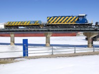 <b>A rare move.</b> Slug POM 2008 and RP20BD POM 1003 are stopped over the Lachine Canal with a short train consisting of lengths of rail on CP flatcars and loaded coil steel cars. This is a rare move, as they are on the CN Wharf Spur (and not Port of Montreal trackage). This is the first time I have ever seen a Port of Montreal train in this section of the port. The train would depart after port security showed up and flagged the nearby crossing. Behind the power is the <i>Algoma Equinox</i>.