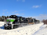 The Société du chemin de fer de la Gaspésie recently repainted two of its ex-CP RS-18's into an SP Black Widow-inspired paint scheme. They are first and third on this windmill train which consists of 72 flat cars holding 48 windmill blades (as well as 1 loaded woodchip car up front), as it rounds a curve and approaches a crossing. These windmill blades are destined for Texas and represent a new business for the Société du chemin de fer de la Gaspésie, which runs this scenic ex-CN line. 