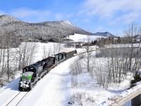 Three ex-CP RS-18's (two recently repainted into an SP Black Widow-inspired paint scheme) lead a train consisting of 72 flat cars holding 48 windmill blades (as well as 1 loaded woodchip car up front), as it approaches an overpass in the town of Carleton-sur-mer, headed for Matapedia and interchange with the CN. These windmill blades are destined for Texas and represent a new business for the Société du chemin de fer de la Gaspésie, which runs this scenic ex-CN line. While much of Eastern Canada has no snow left, there is not shortage of it out here.