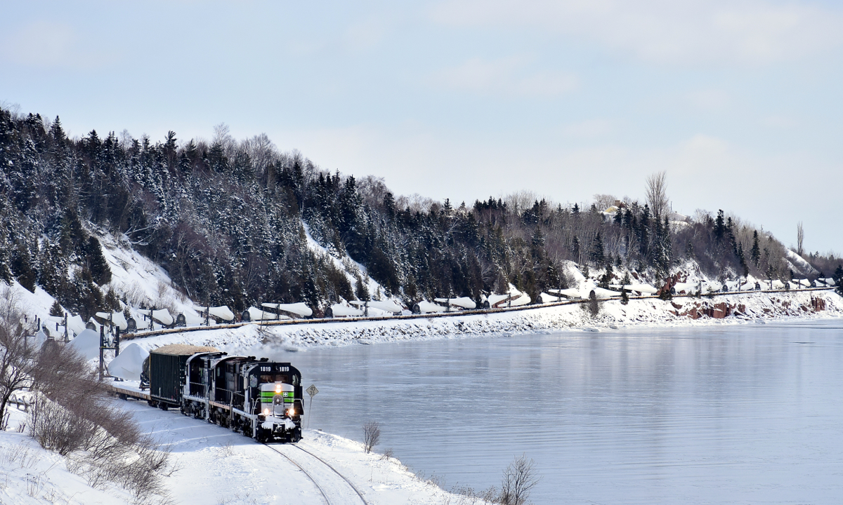 Snaking along the Baie des Chaleurs. Going through a 10 mph section of track, the Société du chemin de fer de la Gaspésie's windmill train slowly snakes along the Baie des Chaleurs, on its way to Matapedia and interchange with the CN. Leading is rebuilt RS-18 SFG 1819.