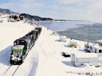 Three ex-CP RS-18's (two recently repainted into an SP Black Widow-inspired paint scheme) lead a train consisting of 72 flat cars holding 48 windmill blades (as well as 1 loaded woodchip car up front), as it rounds the Baie des Chaleurs, headed for Matapedia and interchange with the CN. These windmill blades are destined for Texas and represent a new business for the Société du chemin de fer de la Gaspésie, which runs this scenic ex-CN line.